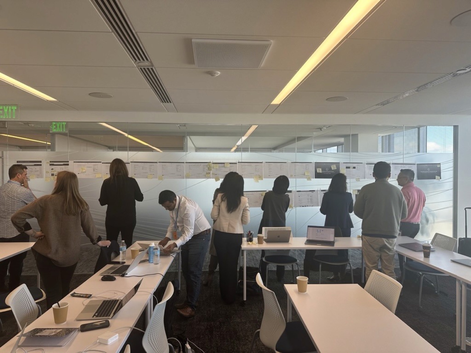 Stakeholders working over printed screens with post-it notes.